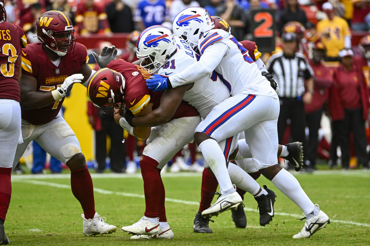 Washington Commanders quarterback Sam Howell sacked by two Buffalo Bills defenders.